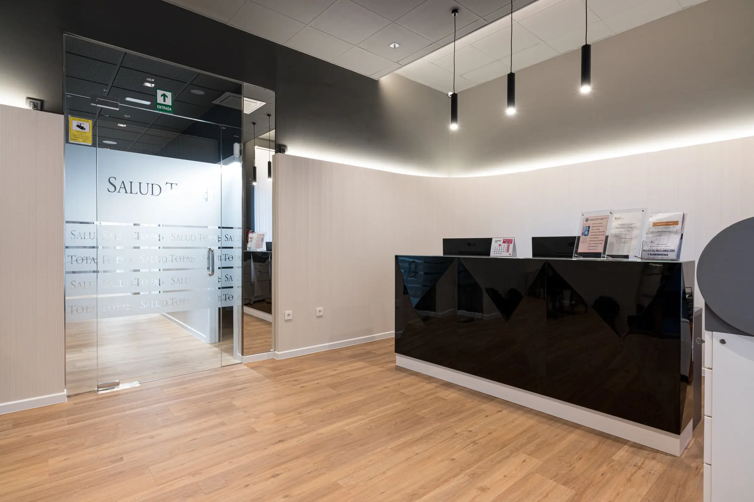 Recepción de Salud Total con mostrador negro y luz indirecta